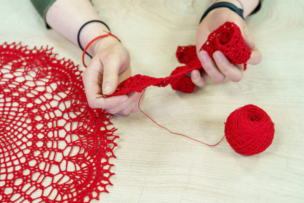 Hands of a craftswoman with a ball of red threads. Unusual hobby crochet. Background with copy space for text - Photo, Image
