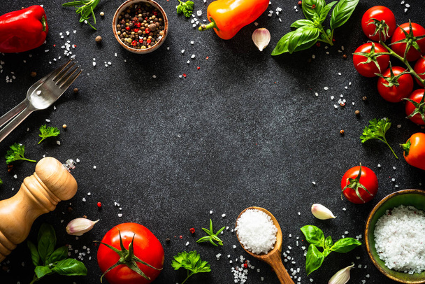 Ételkeret. Étel főzés háttér fekete kő asztal. Friss zöldségek, gyógynövények és fűszerek. Felülnézet másolási hellyel. - Fotó, kép