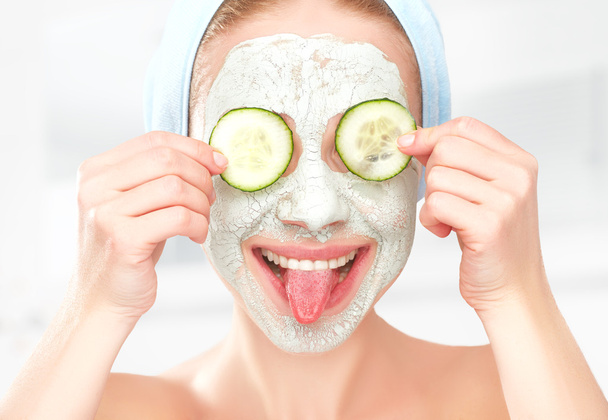 Funny young girl with a mask for skin face and cucumbers - Photo, Image