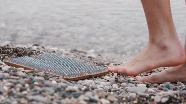 Egy nő odasétál egy fapadlóhoz szadhu szögekkel a tenger mellett. Középső felvétel - Felvétel, videó