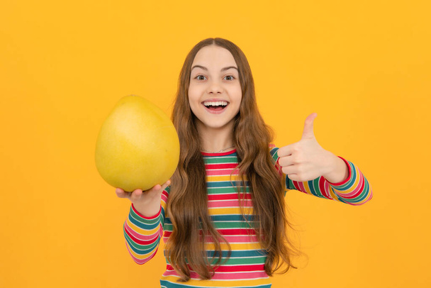 Frutas de verano. Niña adolescente sostiene cítricos pummelo o pomelo, aislado sobre fondo amarillo. Comida saludable para niños - Foto, imagen