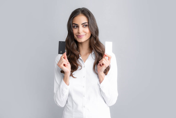 Foto da jovem mulher feliz posando isolado sobre fundo cinza segurando cartão de crédito de débito - Foto, Imagem
