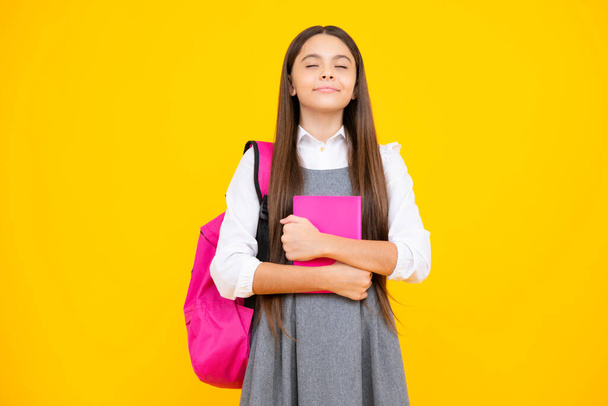 Back to school. Teenager schoolgirl hold book and copybook ready to learn. School children on isolated yellow studio background - 写真・画像