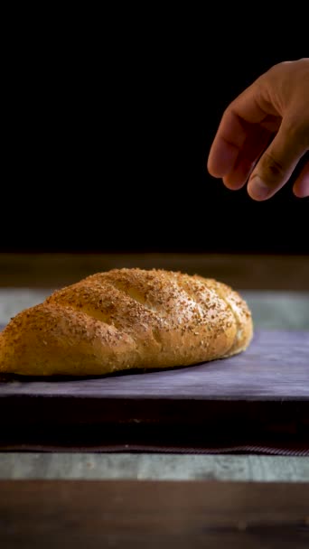 Vídeo vertical de un pan de centeno, salvado de trigo, vídeo en las redes sociales que muestra una mano sosteniendo una barra de pan recién horneado. - Metraje, vídeo