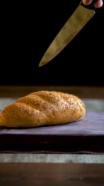 Çavdar ekmeği, buğday kepeği, sosyal medya videosu, elinde bıçakla bir somun taze pişmiş ekmeği keserken elini gösteren dikey video.. - Video, Çekim