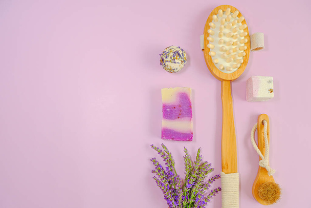 Lavendel badzeep, truffels en natuurlijke borstels en lavendelbloemen op een roze achtergrond. Aromatherapie en spa met lavendelextract. Lichaamscosmetica met lavendelgeur  - Foto, afbeelding