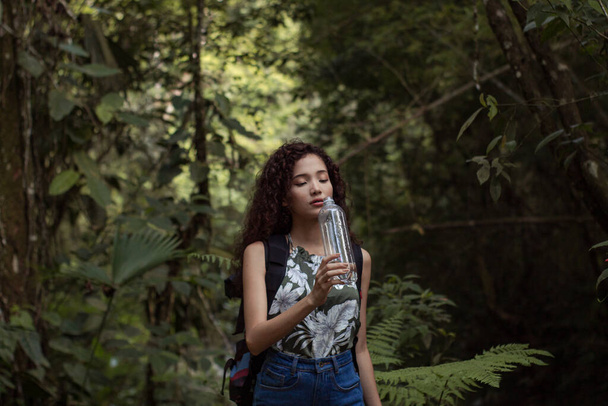 дівчина на прогулянці по лісу, насолоджуючись природою і питною водою
 - Фото, зображення