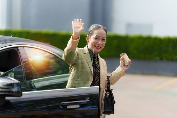 Портрет азіатської старшої ділової жінки виходить з розкішного автомобіля, коли приходить на посаду. Концепція бухгалтерії та фінансів - Фото, зображення