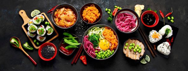 Ассортимент корейской еды на тёмном фоне. Азиатские блюда и закуски действительно кухни. Вид сверху, плоский, панорама - Фото, изображение