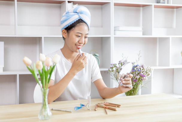 Ázsiai nő teszi a haját a törölköző és a smink, hogy készen áll a munkához, Make up ecset, Miután lezuhanyozott reggel, Szépít, Arcápolás és kozmetikumok, alkotó tükör. - Fotó, kép