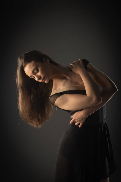 Portrait of beautiful and elegant ballerina girl hugging herself in studio - Photo, Image