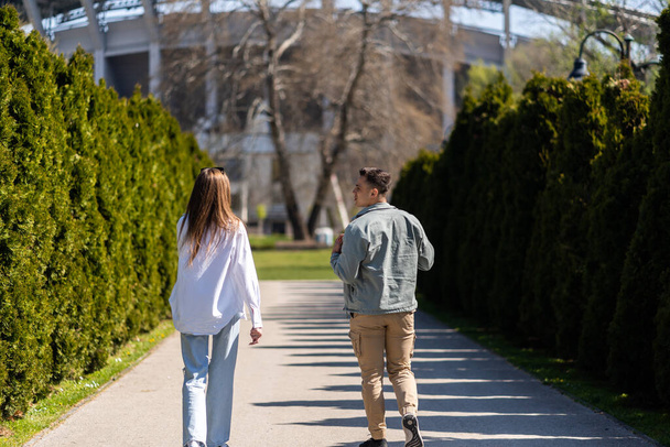 夏の公園で一緒に歩いてカジュアルなスタイルで身に着けている愛の友人の若いカップル - 写真・画像