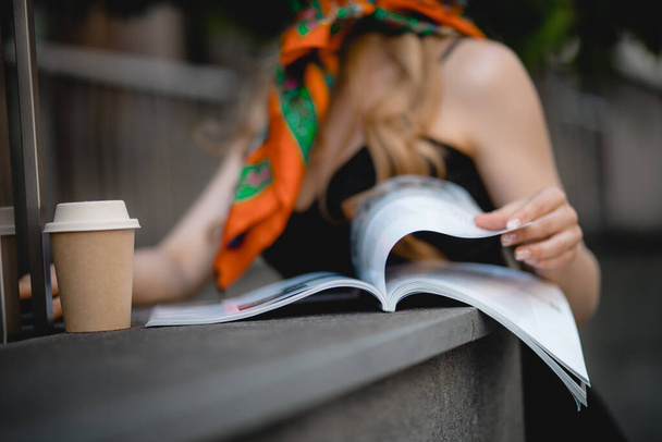 Nierozpoznana kaukaska kobieta czytająca magazyn o modzie w kawiarni z filiżanką kawy, ludzie w mieście, nowoczesne życie, kobieca ręka, styl mody - Zdjęcie, obraz