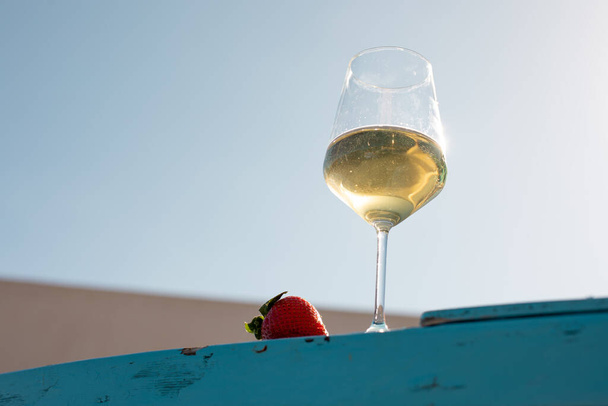 Крупный план винного стекла с белым желтым вином с клубникой. Отдых, романтические путешествия и приключения концепции. Расслабление и радостное настроение. Празднование каникул и праздников - Фото, изображение