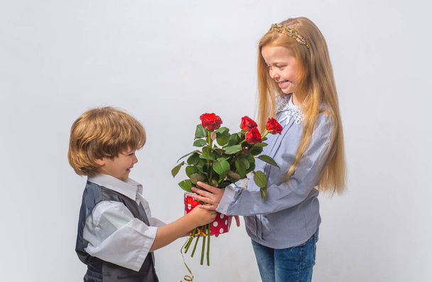 Little Boy with a rose for his teen girlfriend, romantic children. Romantic, boy and girl giving a flower for love and romance - Foto, Imagen