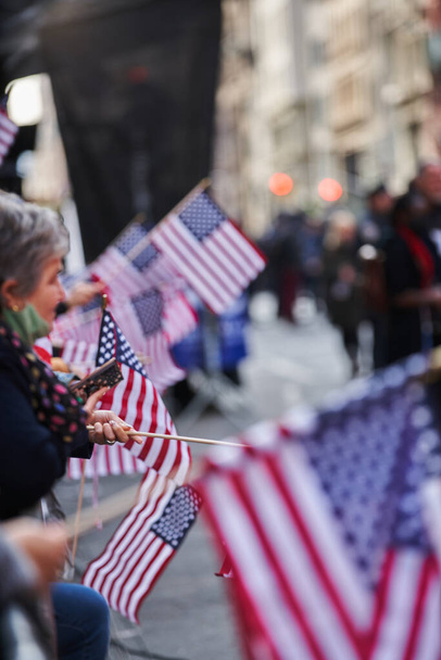 Manhattan, USA - 11. November 2021: People watching Veterans Day Parade in New York City and holding USA flags. Honoring and celebrating Veterans - Fotoğraf, Görsel