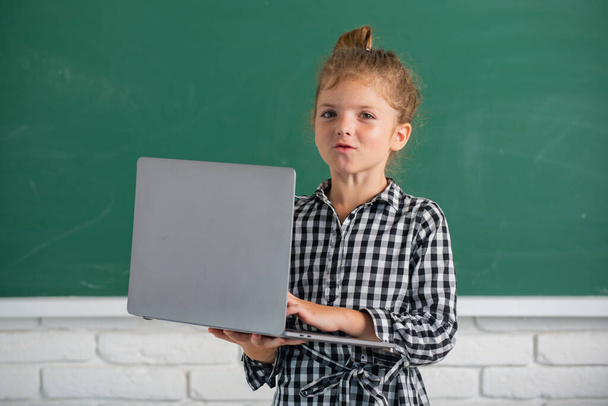 Portrait of attractive cheerful pupil girl using laptop. Kids education, school technology - Photo, image