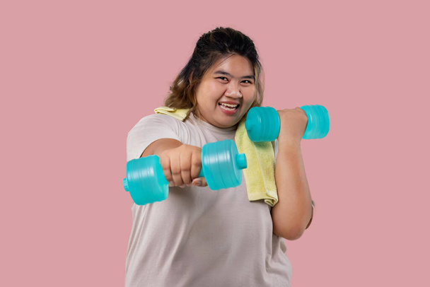 Азиатская большая девочка делает фитнес-упражнения с гантелями изолированы. - Фото, изображение