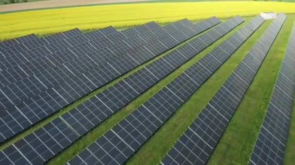 Современные солнечные модули построены возле зеленого поля на солнечной станции в солнечный летний день. Промышленная площадка с солнечными батареями обеспечивает альтернативный вид с воздуха - Кадры, видео