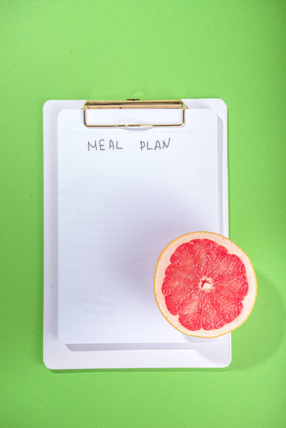 Питание план концепции диеты, с в блокноте, здоровое питание фрукты, овощи, планшеты, ноутбуки и аксессуары для похудения на ярко-зеленом фоне стола - Фото, изображение