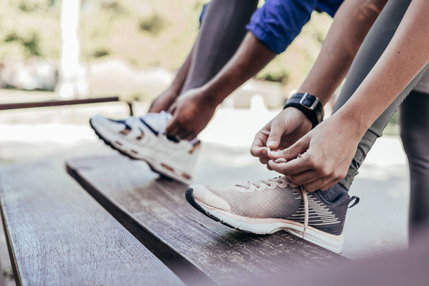 two unrecgonizable runners tying shoelaces before joggin - Fotografie, Obrázek