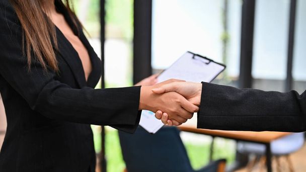 Bizneswoman w formalnych garniturach uścisk dłoni z partnerem biznesowym jako powitanie, pozdrowienia lub podziękowania, partnerstwo lub gratulacje. Obrazek przycięty i zbliżenie - Zdjęcie, obraz