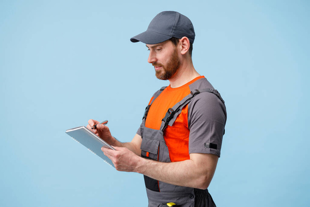 Konzentrierter Mann in Uniform hält Tablet in der Hand und macht sich Notizen. Kopierraum - Foto, Bild