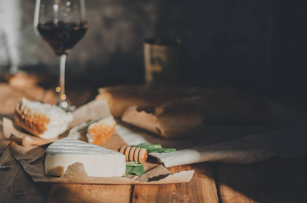 Вечеря з сиром, червоним вином, медом і багет на дерев'яному столі
. - Фото, зображення