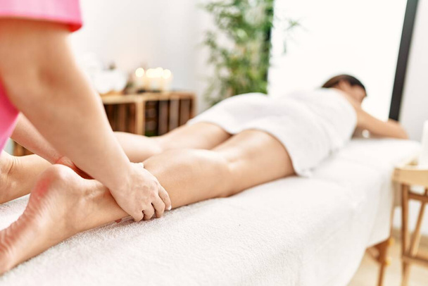 Middle age hispanic woman having legs massage at beauty center - Photo, Image