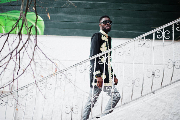 Mega stylish african man in traditional jacket pose. Fashionable black guy in sunglasses. - 写真・画像