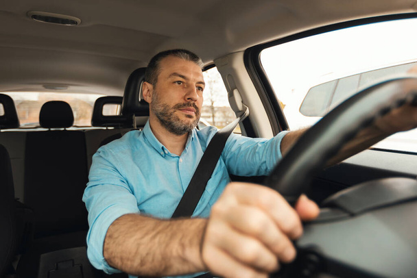 Vážný muž řídí nové auto sedí uvnitř Automobile Riding In City. Shot Of Male Driver Posing With Hands On Steering Wheel In Auto. Vlastnictví vozidel a doprava - Fotografie, Obrázek