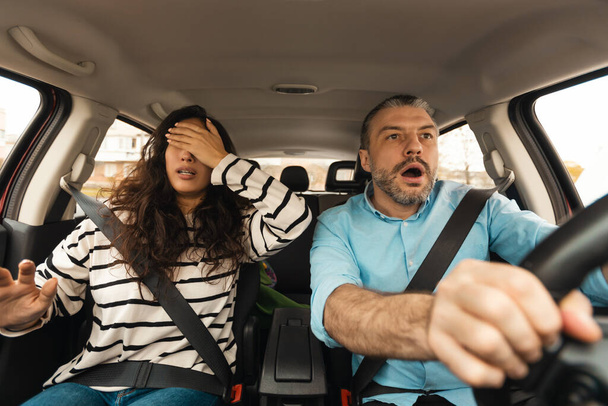 Autounfall. Angstgeplagtes Paar, das Auto fährt, mit Crash-Risiko, Ehefrau, die Augen bedeckt, die in Sitzen im Auto sitzen. Gefährliches Verkehrskonzept. Selektiver Fokus - Foto, Bild