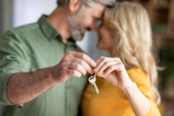 Szoros lövés a romantikus középkorú pár holding Home Keys kezükben, miután költözött az új ház, boldog érett házastársak ünnepli vásárol az első ingatlan, szelektív fókusz, vágott - Fotó, kép