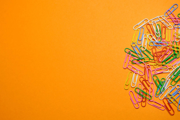 Colored paper clips on a orange background - Φωτογραφία, εικόνα