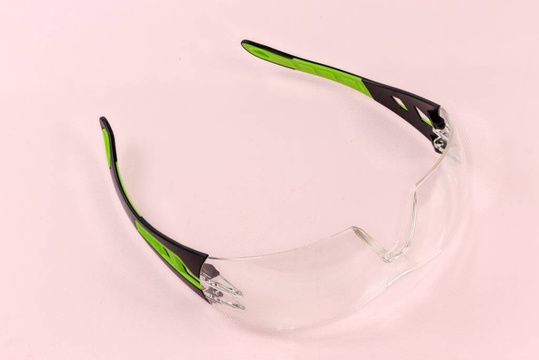 Ballistic protective eyewear with plastic eyeglass temples on a light pink surface - Photo, Image