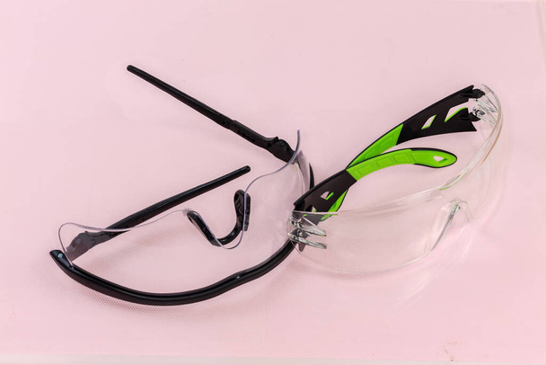 Deux lunettes de protection balistique différentes avec des branches de lunettes en plastique sur une surface rose clair - Photo, image