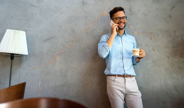 Portrait of successful business man talking on smartphone in coffee break in corporate office - Photo, Image