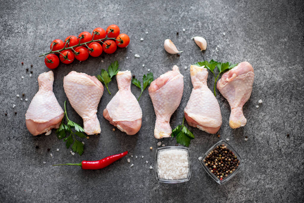 raw chicken legs with spices, vegetables and herbs on black background - Foto, Imagem