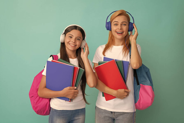 family help. mother and daughter hold notebook. back to school. childhood online education. cheerful pupil and student. mom and teen girl in headphones. private teacher and child carry backpack. - Photo, Image