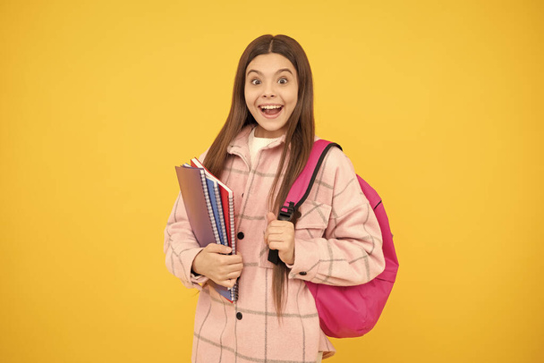 niña sorprendida usar camisa a cuadros rosa llevar bolso de la escuela y cuadernos, estudio. - Foto, imagen