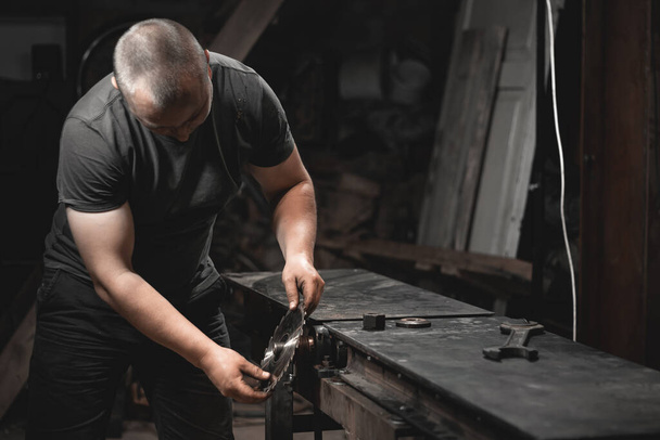 Um trabalhador prepara uma máquina de trabalhar madeira para o trabalho em sua oficina doméstica. Fazendo produtos metálicos com suas próprias mãos - Foto, Imagem