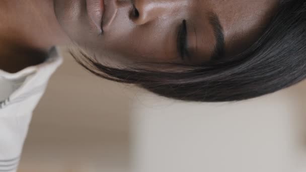 Vista vertical close-up media cara femenina seria joven afroamericana mujer con ojos marrones mirando a la cámara problema de visión procedimiento de corrección láser publicidad feminismo belleza natural cosmetología - Metraje, vídeo