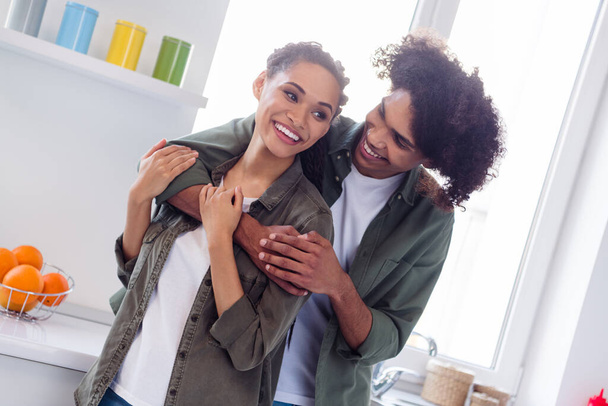 Photo of happy positive lovely girlfriend and boyfriend spend time together in kitchen room hug embrace each other. - Photo, image