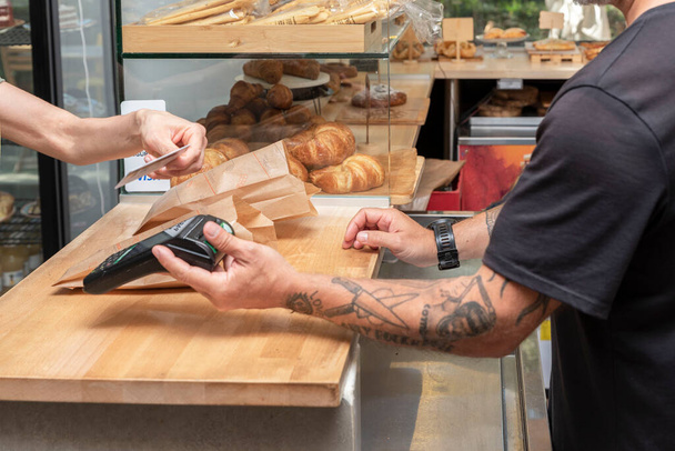 payment with the card for a purchase in the bakery store - retail sales concept - 写真・画像