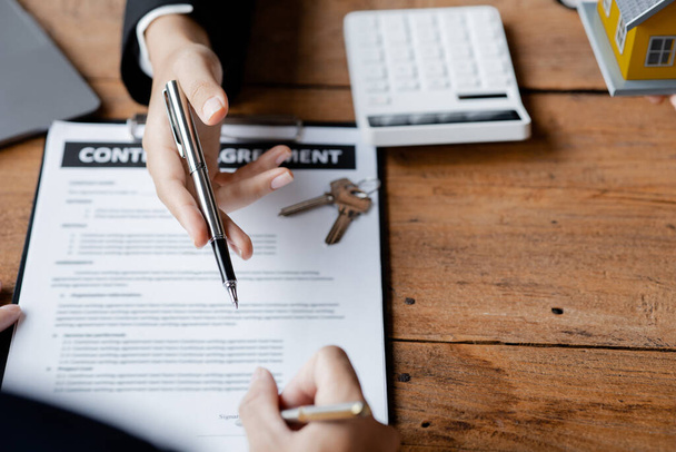 Rental company employee is discussing the details before the customer agrees to sign a rental contract, explaining the details and the terms and conditions of the rental. Real estate rental ideas. - 写真・画像