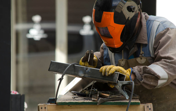 kovář pracující s bodovým svářečem, svařování pracovníkem s ochrannou přilbou - Fotografie, Obrázek