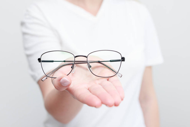 Μια γυναίκα κρατάει γυαλιά για να διορθώσει την όραση. κοντινό πλάνο - Φωτογραφία, εικόνα