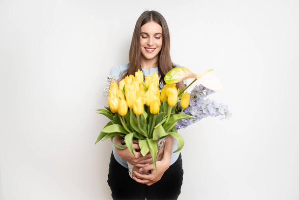 Jeune femme heureuse tenant différentes fleurs. Fleuriste avec fleur. Photo de haute qualité - Photo, image