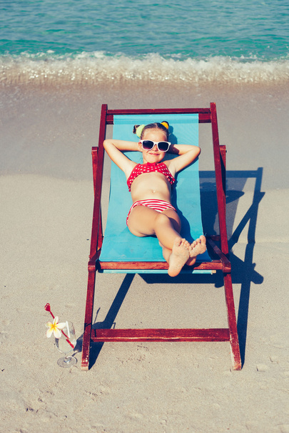 Young lady relaxing in a chair on a tropical beach with white sand - Foto, Imagem