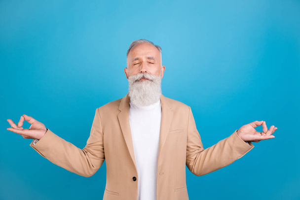 Portrait of handsome elegant dreamy grey-haired man meditating isolated over bright blue color background. - Foto, immagini